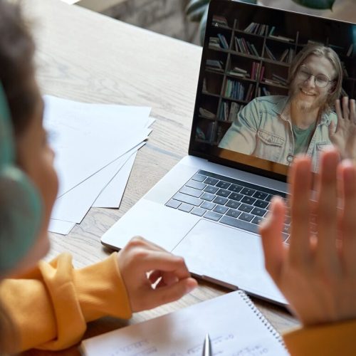 Hispanic teen girl distance learning with online teacher on laptop screen.